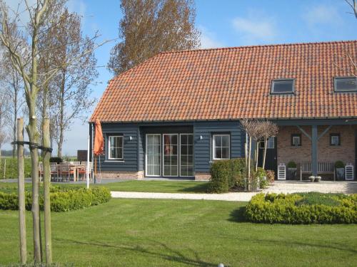 a house with a red roof and a yard at Stylish Holiday Home in Zuidzande with Sauna in Zuidzande