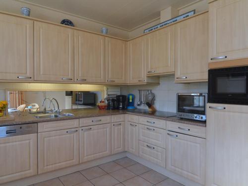 a kitchen with wooden cabinets and a sink and a microwave at Quaint Farmhouse in Haarlo near the Forest in Haarlo