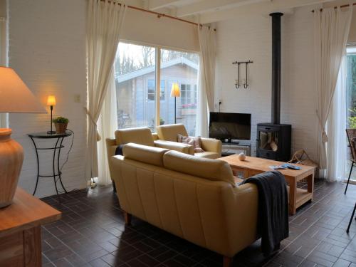 een woonkamer met een bank en een tv bij Modern bungalow in South Holland in Noordwijkerhout