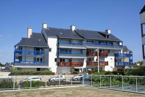 - un grand immeuble avec des voitures garées devant dans l'établissement REF 005 Studio pour deux personnes avec terrasse résidence avec piscine PORT CROUESTY ARZON, à Arzon