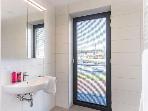 La salle de bains est pourvue d'un lavabo et d'une fenêtre. dans l'établissement New and tasteful apartment with a panoramic view over the marina, à Kamperland