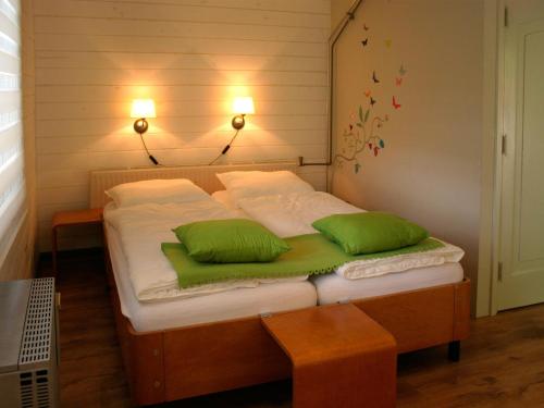 オーテマルスムにあるCosily furnished chalet with microwave, in a holiday park in Twenteのベッド1台(上に緑の枕2つ付)