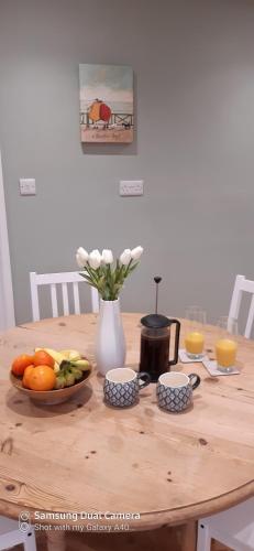 a wooden table with a bowl of fruit and a vase of flowers at Hartendale in Flamborough