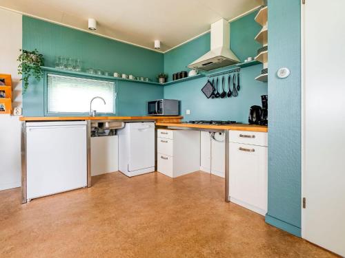 una cocina con armarios blancos y una pared azul en Lovely Chalet near the Lauwersmeer Lake, en Anjum