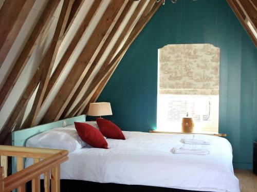 Un dormitorio con una cama con almohadas rojas y una ventana. en Luxury VOC Stay w Views, en Enkhuizen