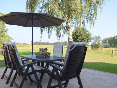 a black table with two chairs and an umbrella at Farmhouse in Geesteren near Forests in Geesteren
