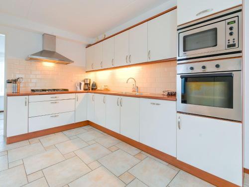 - une cuisine avec des armoires et des appareils blancs dans l'établissement Captivating Holiday Home in Zeewolde near Forest, à Zeewolde