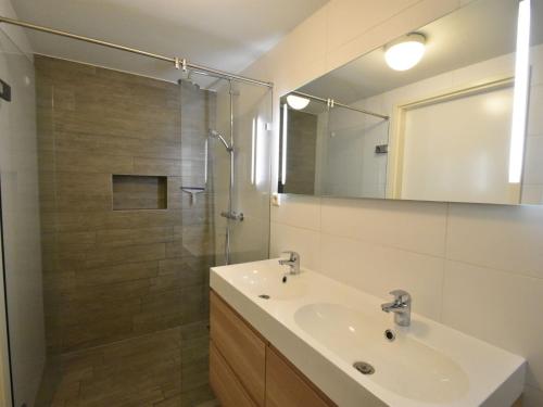 ein Badezimmer mit Waschbecken und Dusche mit Spiegel in der Unterkunft Bungalow near Veerse Meer with Private Garden in Kamperland