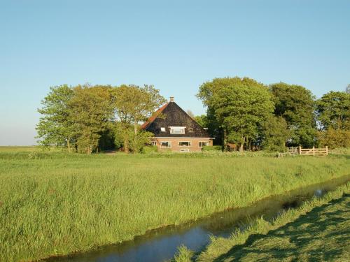 an old house in a field next to a river at Rural holiday home with a lovely sunny terrace in Workum