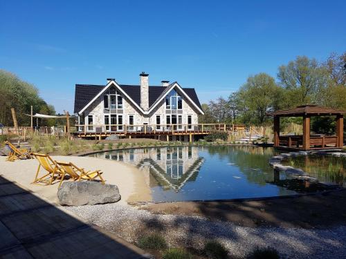 ein großes Haus mit einem Teich davor in der Unterkunft Luxurious Holiday Home with bubble bath in Noordwijk in Noordwijk