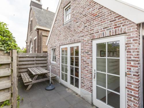 a brick building with a door and a bench at Sunny holiday home near the sea in Wemeldinge