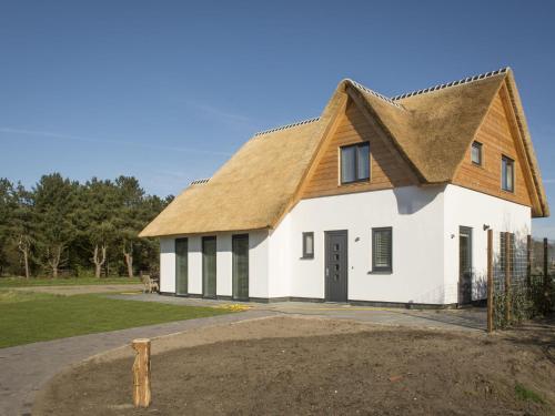 un grand bâtiment blanc avec un toit de chaume dans l'établissement Ritzy villa in De Cocksdorp Texel with terrace, à De Cocksdorp
