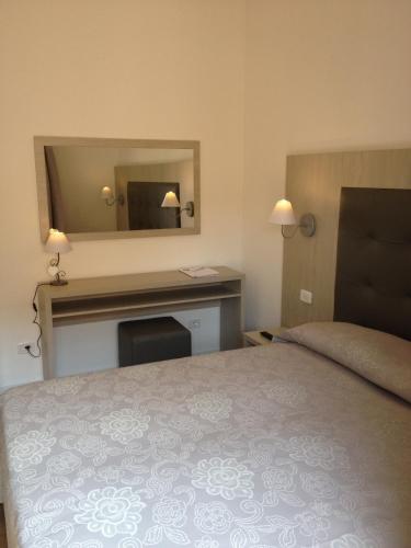 a bedroom with a bed and a desk with a mirror at Hotel Lucerna in Castiglione della Pescaia