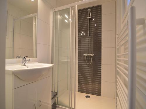 een witte badkamer met een wastafel en een douche bij Nice chalet with dishwasher and wooded location in Vorden