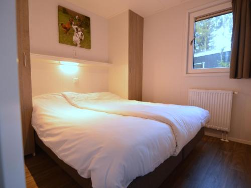een slaapkamer met een groot wit bed en een raam bij Nice chalet with dishwasher and wooded location in Vorden