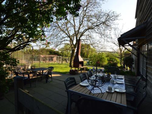 ベルヘン・オプ・ゾームにあるSpacious farmhouse in Bergen op Zoom with fenced gardenの木製テーブルと椅子付きのパティオ