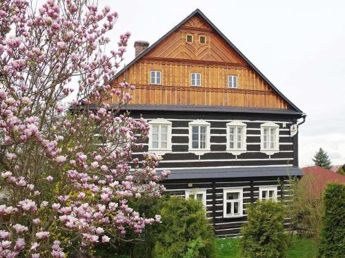 uma casa preta e branca com flores cor-de-rosa à frente. em Rodinný penzion Dřevěnka-Kulturni Pamatka em Bozkovska