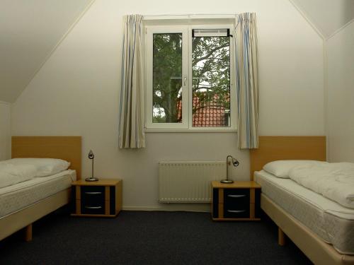 ヴェステルボルクにあるHoliday home Vakantiepark Het Timmerholt 5のベッド2台と窓が備わる客室です。