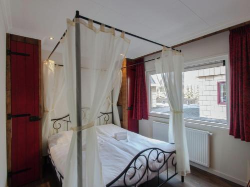 Un dormitorio con una cama con dosel y una ventana. en Villa in De Bult with modern comforts, en De Bult