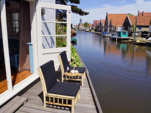 ヒンデローペンにあるLovely holiday home in Hindeloopenの運河を見渡すバルコニー(椅子2脚、テーブル付)