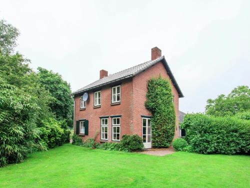 a large red brick house with a green yard at Beautiful Holiday Home in Lage Mierde with Fireplace in Lage Mierde