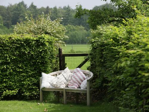 a bench with pillows on it in a garden at Peaceful Farmhouse in Doorn near Forest in Doorn