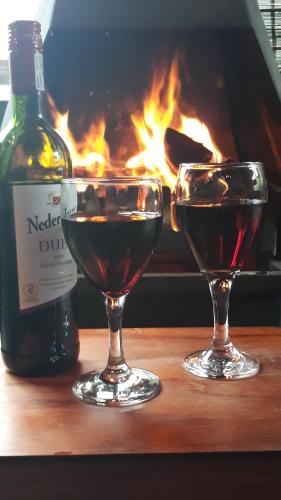 two glasses of red wine and a bottle of wine at Kings Lodge Hotel in Hogsback