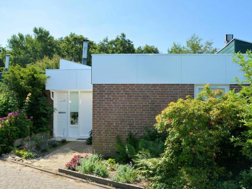 een stenen huis met een witte deur in een tuin bij Fresh and colorful holiday home near the beach sea dunes and lake in Noordwijkerhout