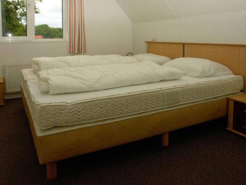 een groot bed met witte lakens en kussens erop bij Spacious holiday home with a dishwasher, 20km from Assen in Westerbork