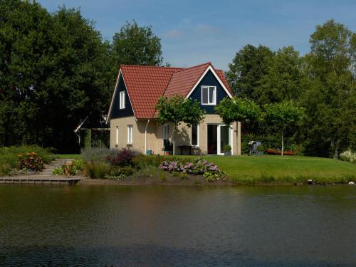 una casa con techo rojo junto a un lago en Spacious holiday home with a dishwasher, 20km from Assen, en Westerbork