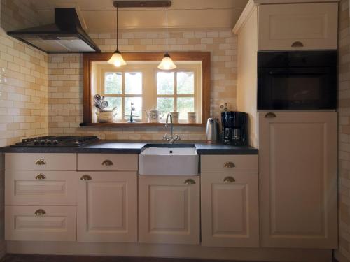 a kitchen with white cabinets and a sink and a window at Farmhouse in Enschede near Forest in Enschede