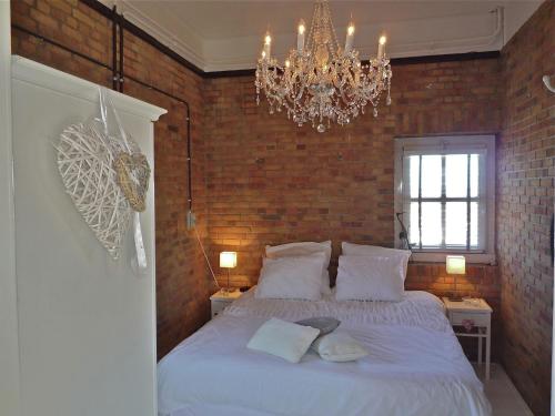 a bedroom with a large white bed with a chandelier at Heritage Holiday Home in Huisduinen near Sea in Huisduinen