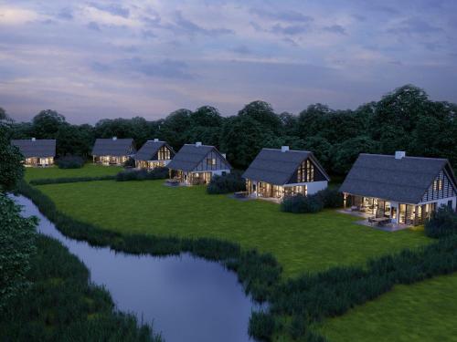 an aerial view of a row of cottages on a field with a river at Luxury villa with sauna near beach in De Cocksdorp