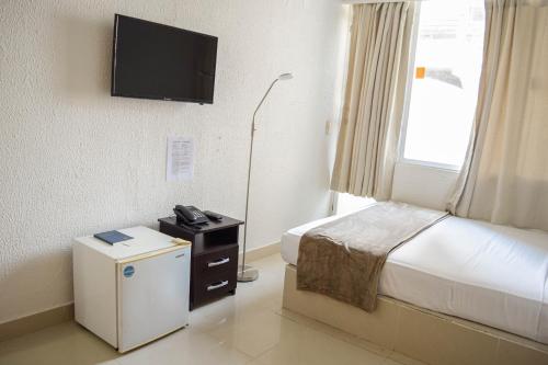 a hotel room with a bed and a television on the wall at Hotel Cartagena Premium in Cartagena de Indias