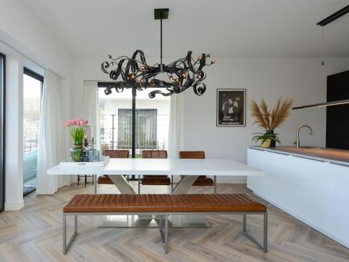 a dining room with a white table and a chandelier at Luxury villa on the waterfront with jetty in Zeewolde