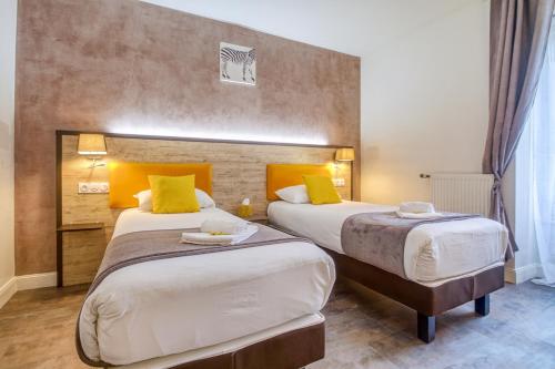 a hotel room with two beds with yellow pillows at Hôtel Saint Albert in Sarlat-la-Canéda