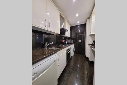 a kitchen with white cabinets and a sink at Marble Home - São Sebastião in Lisbon
