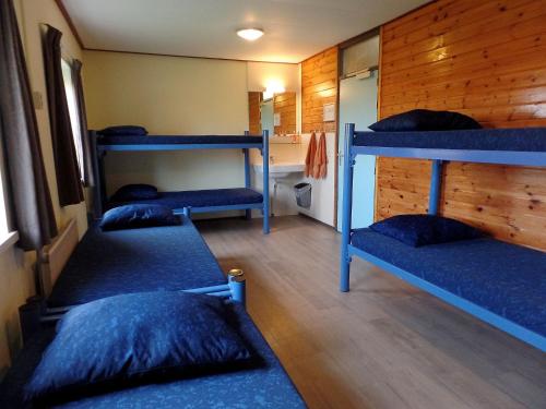 a room with three bunk beds in a cabin at Stone house with private pool and garden in quiet place in Ellemeet