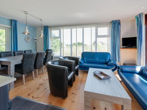 a living room with a blue couch and a table at Beautiful dune villa with thatched roof on Ameland in Buren