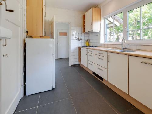 cocina con armarios blancos y nevera blanca en Beautiful dune villa with thatched roof on Ameland en Buren