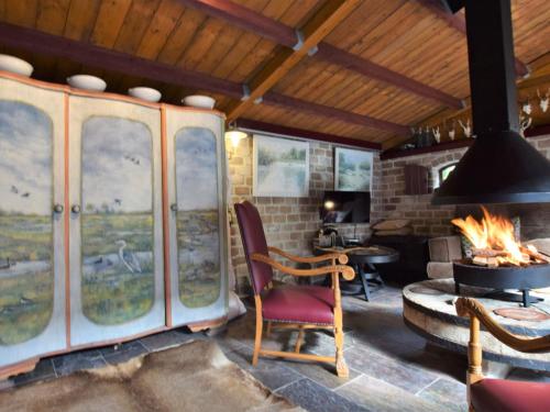 een kamer met een open haard, een stoel en een tafel bij Cozy holiday home with a hot tub in Musselkanaal