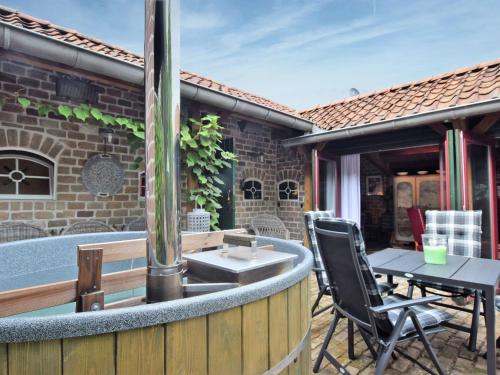 a patio with a hot tub and a table and chairs at Cozy holiday home with a hot tub in Musselkanaal