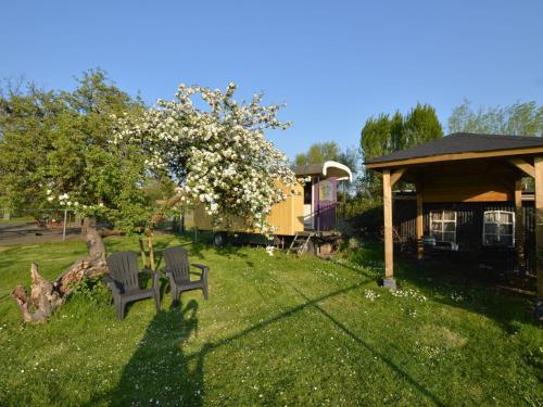 un cortile con due sedie e un albero con fiori bianchi di Holiday Home in Bergen op Zoom with Garden a Bergen op Zoom
