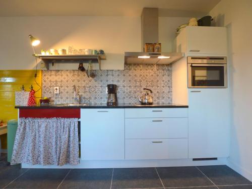 cocina con armarios blancos y fogones en Cosy holiday home on a farm in Zeeland, en Zelanda
