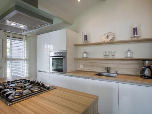 a kitchen with white cabinets and a stove top oven at Attractive holiday home with large terrace in Kattendijke