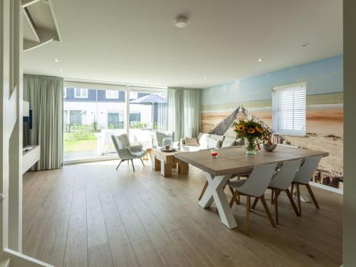 een woonkamer met een tafel en stoelen en een bank bij Luxurious villa a 5 minute walk from beach in Cadzand