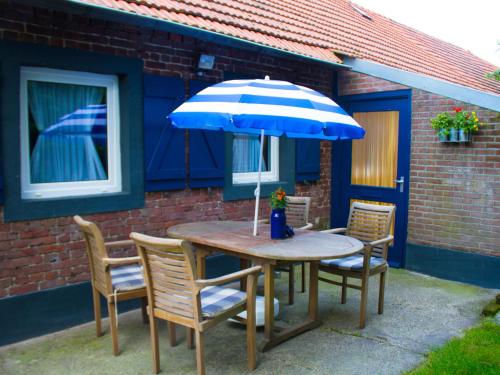 un tavolo in legno con sedie e ombrellone di Holiday home in North Limburg with enclosed garden a Ospel