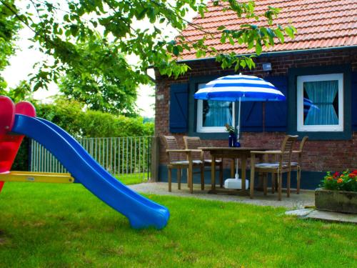 uno scivolo in un cortile con tavolo e ombrellone di Holiday home in North Limburg with enclosed garden a Ospel