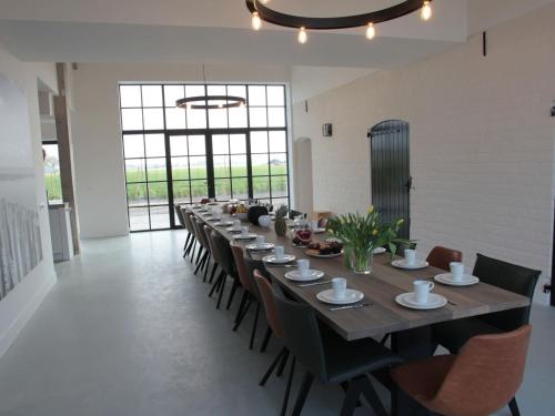 a long dining room with a long table and chairs at Elegant Farmhouse in Zuidzande with Private Garden in Zuidzande