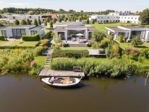a boat on the water in front of a house at Luxury villa with private jetty in quiet park in Zeewolde